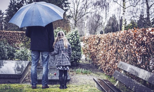 dziewczynka z tatą przy grobie na cmentarzu