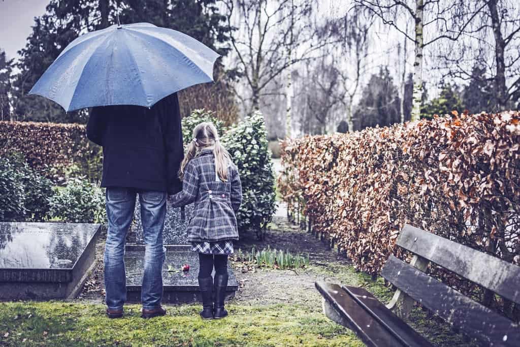 dziewczynka z tatą przy grobie na cmentarzu