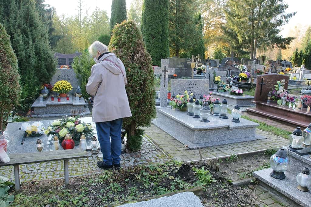 kobieta odwiedzająca bliskich na cmentarzu w Święto Zmarłych