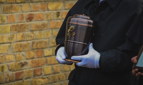 Pogrzeb urnowy, pracownik zakładu pogrzebowego trzymający urnę
